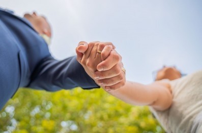 Personas casadas con las manos unidas y anillos de compromiso